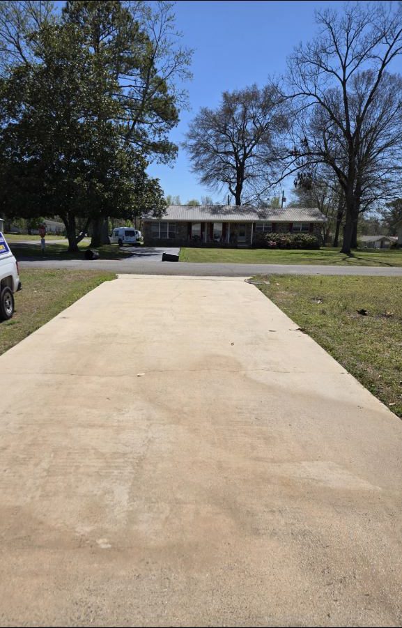 Long residential driveway after pressure washing, concrete bright and even from street to garage